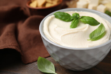 Delicious tofu sauce and basil leaves in bowl on wooden table, closeup. Space for text