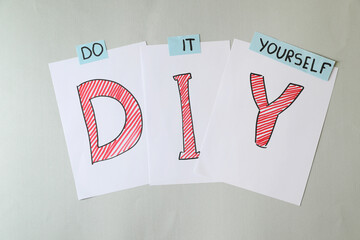 Phrase Do It Yourself and abbreviation DIY made of letters on light grey background, flat lay