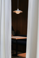 Wooden round table with ceiling lamp and white curtain in cafe or restaurant decoration minimal style.  Display, Background and wallpaper.