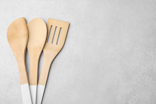 Set of wooden cooking utensils on light grey table, flat lay. Space for text