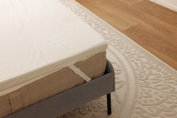 Fototapeta na wymiar White memory foam mattress topper on grey bed indoors