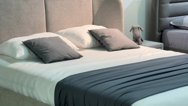 Made double bed with white and gray pillows and textile headboard in a furniture store