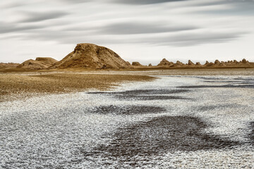 Fototapeta na wymiar Yardang landforms landscape with long exposure clouds and dried salt lake