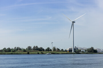 A wind generator stands in the Netherlands near a river A sunny summer day. Ecology, green energy and saving the planet. 