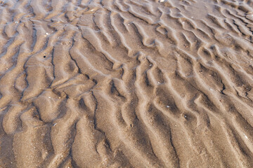 Texture of sand on the seashore. Tide. Curved lines in close-up. Background.