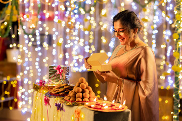 Portrait of smiling beautiful woman with gift box during diwali festival.