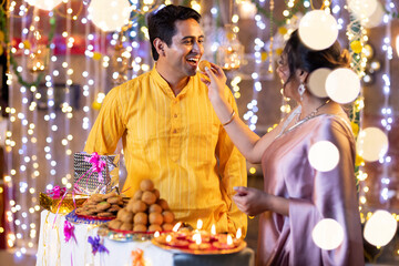 Obraz premium Indian smart couple eating sweet laddu on Diwali, selective focus