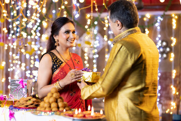 Happy man with surprise gift for wife on the occasion of festival celebration