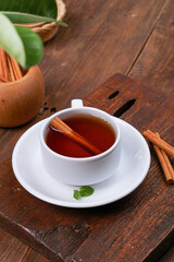 a cup of tea and cinnamon with a dark mode theme on a brown wood background