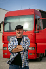 Middle age Caucasian truck driver standing confident in front of his vehicle, hands in pockets 