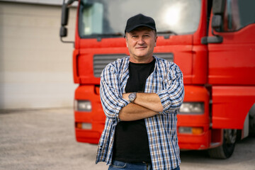 Caucasian man in his fifties with cap and crossed arms standing in front of red truck 