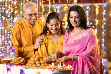 Happy grandparents and granddaughter playing with sparkler crackers on the occasion of Diwali festival celebration
