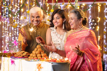 Happy grandparents and granddaughter playing with sparkler crackers on the occasion of Diwali festival celebration