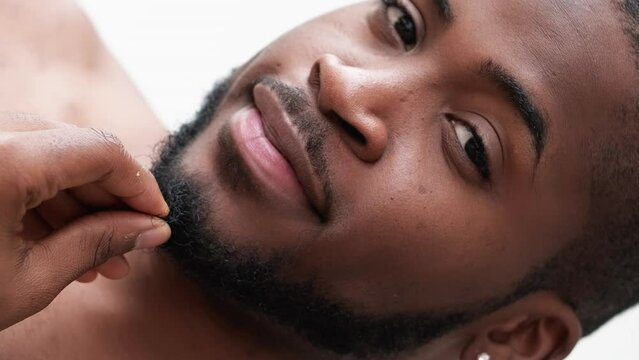 Vertical video. Beard care. Metrosexual lifestyle. Confident satisfied handsome shirtless man touching face skin hair isolated on white background.