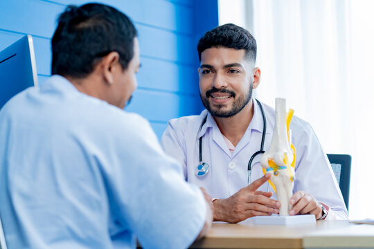 Asian male orthopedics professional doctor consulting explaining knee bone model to male patient, Physiotherapist explain an anatomical human knee-joint to an elderly patient. Concept physio treatment