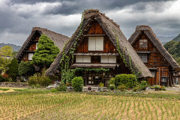 Fototapeta na wymiar Three houses on a cloudy day in the village of Shirakawa-gō, Japan