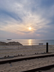 Obraz premium A sunrise at the beach and a railroad covered in sand.