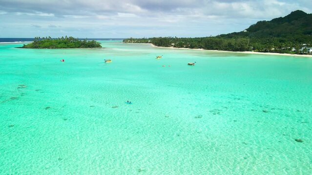 Couple paddling Muri Lagoon in Rarotonga at high tide with mountains in the background.