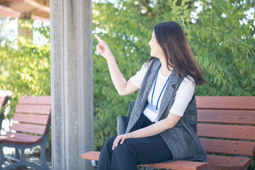 ベンチに座ってハンドサインする女性　hand sign