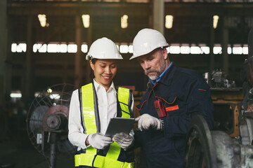 Male and female engineer worker working with tablet computer inspecting of factory in the industry factory