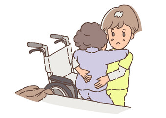 介護士に、ベットから車椅子に移動を介添えしてもらっている、おばあさん。