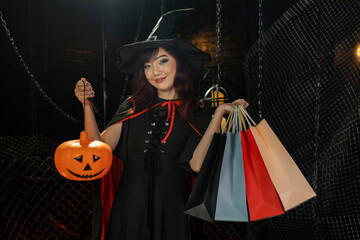 Asian girl in witch costume holding jack'o lantern for halloween party trick or treat concept with dark black background