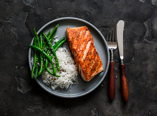 Delicious healthy lunch - grilled salmon, basmati rice and green string beans on a dark background,...