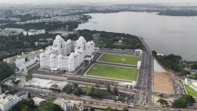 Aerial footage of the Telangana Secretariat and Martyrs Memorial situated in Hyderabad. The Telugu Thalli Flyover and NTR Marg roads are used by vehicles at night. Hussain Sagar Lake.