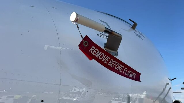 Remove before flight strap pitot cover on a modern jet from outside.daylight. Slowmotion.
