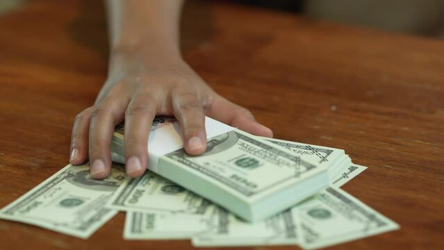 Close-up of a young woman's hand giving a lot of money to a businessman