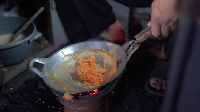 Kerak Telor is a traditional food from Jakarta made from duck egg mixed with sticky rice grated coconut. The seller is cooking egg crust or kerak telor in a small wok with a charcoal stove. 