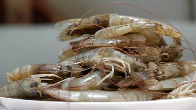 There are shrimps on a table, both in a plate and in a bowl, either at home or in a restaurant