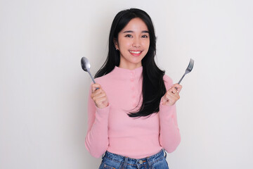 Asian young woman smiling while holding a spoon and fork