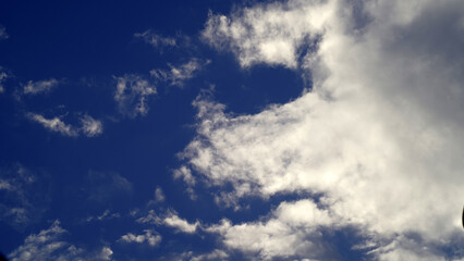 Cumulus or cluster moving clouds with blue sky background in sunny weather in a wide angle shot