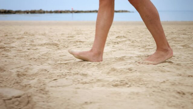 Sand cushioning barefooted person walking along the beach keeping active