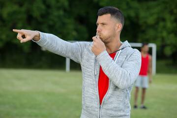 referee blowing whistle and pointing forwards