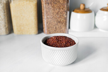 Red quinoa on the white plate on the background of a modern kitchen. Healthy food and nutrition concept. Safe, ecological, and healthy products