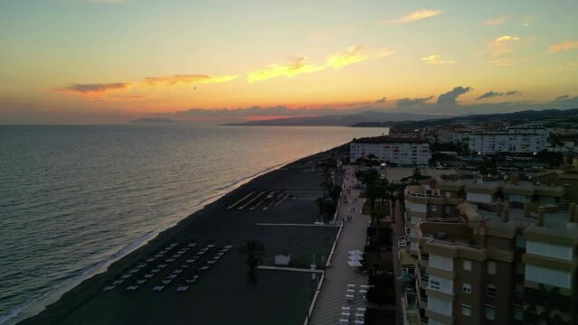 Sun Loungers And Beachfront Hotels On A Sunset At Playa de Torrox In Malaga, Spain. aerial