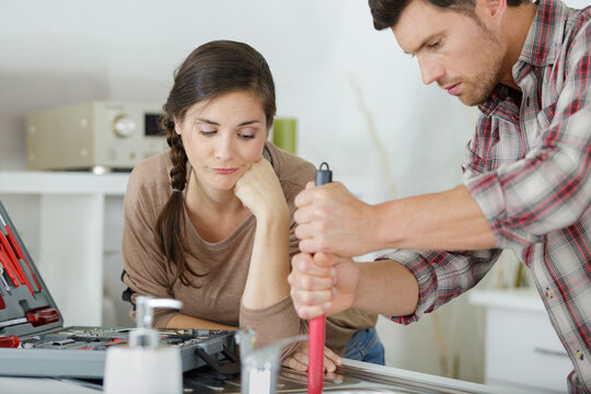 upset couple fixing kitchen sink