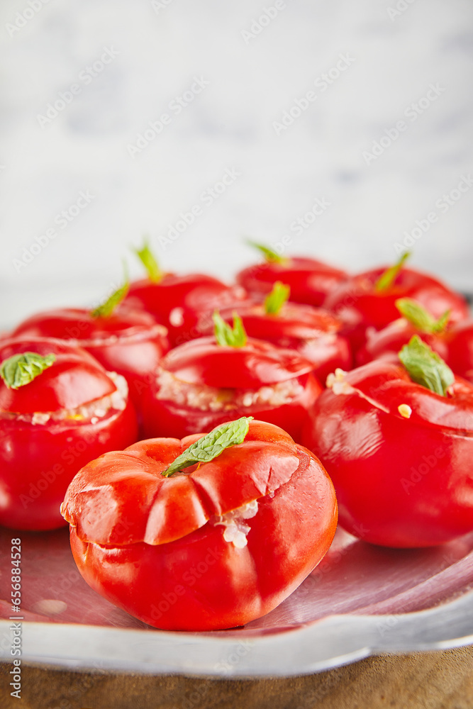 Wall mural Stuffed tomatoes with basil leaf on board on light background