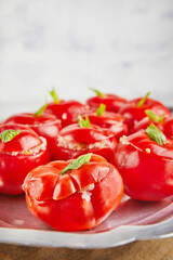 Stuffed tomatoes with basil leaf on board on light background