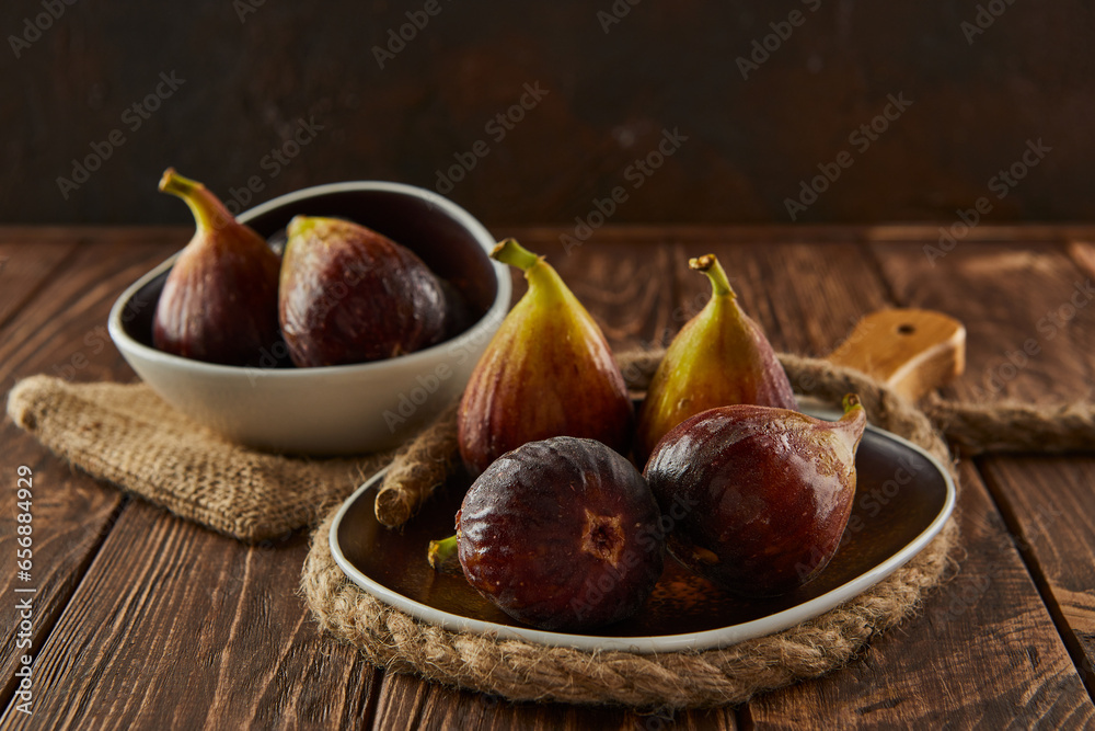 Poster Figs on wooden background and glass plates with hard shadows on burlap