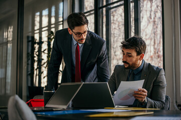 Two confident businessmen engaged in a productive meeting, discussing business strategies and sharing ideas in a modern office setting