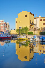 Fototapeta na wymiar Panoramic view of colorfull houses and moored yachts in Port Saplaya. Houses and boats reflected in the water. Valencia's Little Venice.