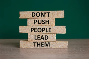 Fotobehang Push or lead people symbol. Concept words Do not push people lead them on brick blocks. Beautiful wooden table green background. Business Push or lead people concept. Copy space. © Liudmila