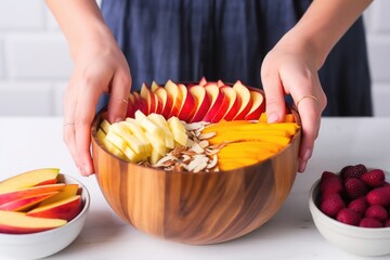 Obraz na płótnie Canvas hand placing sliced peaches on top of an acai bowl