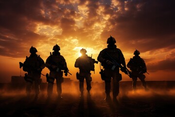 The military silhouettes of soldiers hold gun against with sunset sky background.