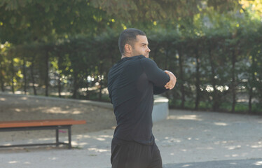 Young male jogger athlete training and doing workout outdoors in city. 