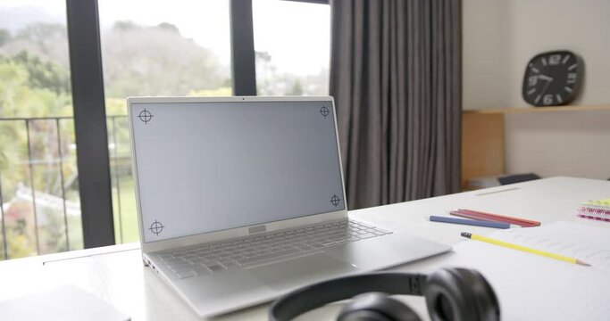 Close up of laptop with copy space on screen and headphones on desk, slow motion