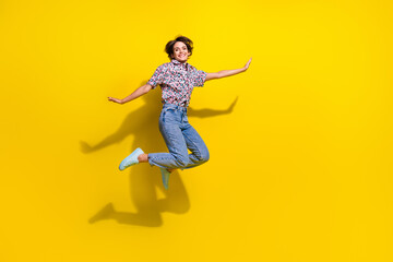 Full length portrait of crazy satisfied person jumping flying empty space isolated on yellow color background